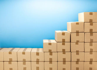 Cardboard boxes steps up for delivery or moving. Stack of boxes and blue background. Copy space for text