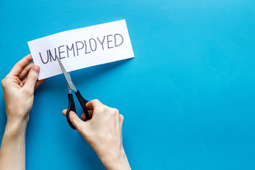 Employment, new job concept. Hands cut paper -unemployed - on blue desk from above copy space