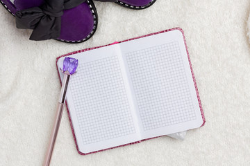 Notepad, purple women's shoes, pen and condom lie on a white soft background.
