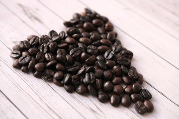 Coffee beans in the form of a heart lie on a wooden table