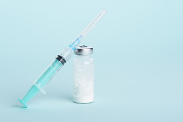 medical syringe, glass ampoule on blue background with copy space, vaccination