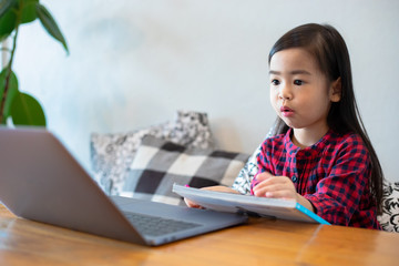 Asian girl or daughters use notebooks and technology for online learning during school holidays and watching cartoons at home. Educational concepts and activities of the family