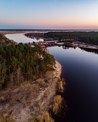 Areal drone view of small river near pine tree forest.