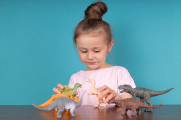 Cute little girl having fun playing with a toy dinosaurs