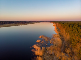 Obraz premium River Lielupe Coutnryside view in sunset near shoreline with beautiful pine tree forest.