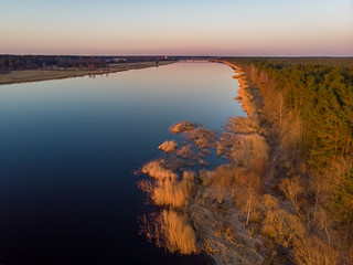 River Lielupe Coutnryside view in sunset near shoreline with beautiful pine tree forest.