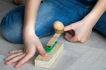 A child at home shoots a walnut at a target from a handmade catapult