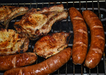 Pork pieces of meat and home-made sausages are grilled on barbeque