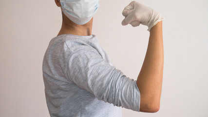 Woman with a white medical mask and latex - "We Can Do It!"  Rosie the Riveter of today. Fighting the corona virus.