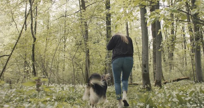 Woman take off face mask running free with her female dog smiling on a forest trail in nature park on a post coronavirus staycation travel