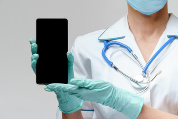 medical doctor nurse woman wearing protective mask and gloves - using mobile phone