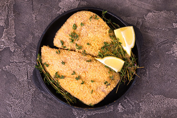 Raw ready to cook chicken breast fillets with breading, lemon, thyme