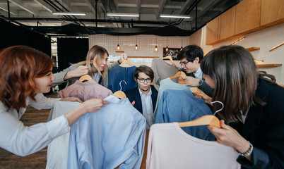 Young stylist looking through set of shirts for fashion shooting