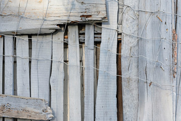 Fragment of an old fence. Texture of metal mesh and wooden boards