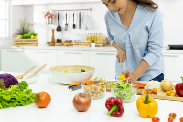 Young Woman Cooking in the kitchen. Healthy Food - Vegetable Salad Diet. Healthy Lifestyle. Cooking delicious food during the COVID-19 self-quarantine 14 days. Stay at home concept.