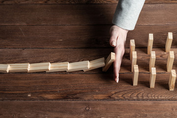 Businesswoman protecting dominoes from falling