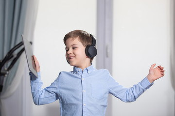 technology - a lovely young pupil rejoicing and jumping with his tablet wearing headphones and smiling