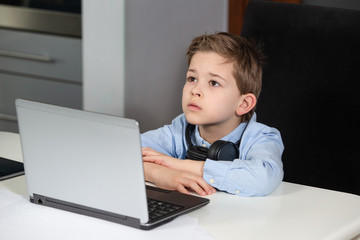 e-learning from home - tired young boy working with his computer being sad and looking up
