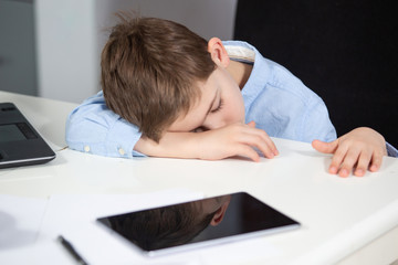 learning from home - lovely young boy in blue shirt sleeping at the table being overworked