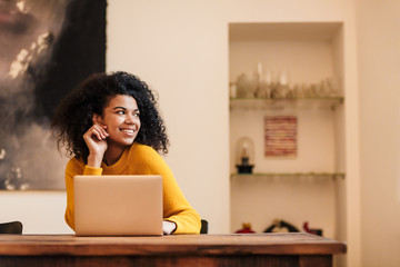 Image of african american woman using laptop while sitting at table
