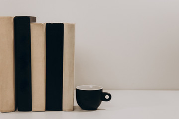 Black and white books and  cup of coffee on gray isolated background