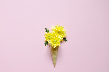 Waffle cone with yellow chrysanthemum flowers on a pink background.