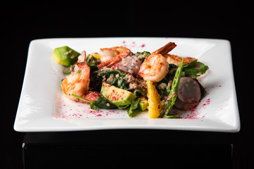 Fried king prawns with brown rice and vegetables: red pepper and onions. Served on a wooden plated with cut chives, spring onions and two pieces of lemon.Macro perspective, nobody, restaurant, menu.
