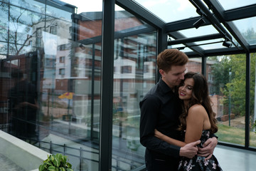 beautiful couple-a girl in a magnificent dress and a guy in a black shirt and trousers are in a building with a beautiful interior