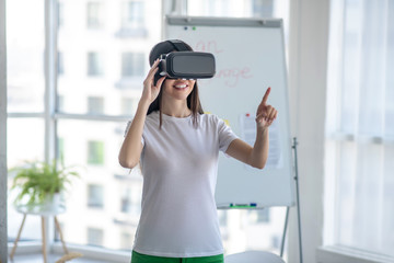 Dark-haired girl standing wearing vr headset and feeling interested