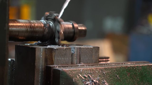 Old industrial milling machine for cutting metal in the process. A jet of coolant is directed to the cutters.