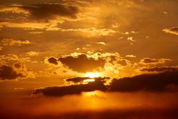 Beautiful landscape of red-orange sunset behind clouds in a blue sky