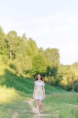Portrait of a young beautiful girl in a sundress. Summer photo session in the park at sunset.