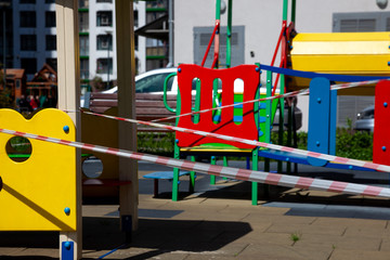 Fototapeta na wymiar Indoor playgrounds during the coronavirus epidemic. A red ribbon is wrapped in a playground - a ban on visiting parks and public places during a pandemic. Children's houses and slides on the street.