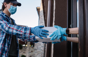 Courier and protective mask delivers parcels, customer and medical gloves receives box. Delivery service under quarantine, disease outbreak, coronavirus covid-19 pandemic conditions.