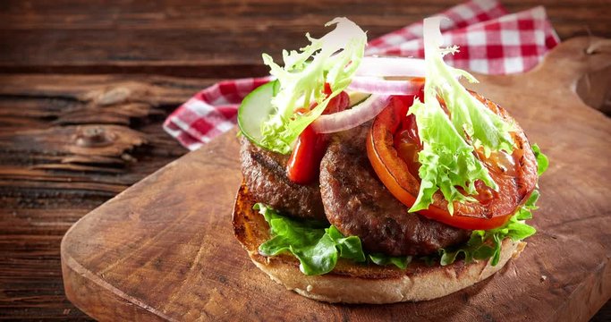 American barbecued burger with fresh ingredients in a stop motion footage on rustic wooden background for steakhouse concept