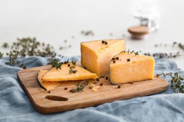 Wooden board with tasty cheese, thyme and spices on table