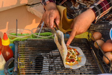 stuffed pancake is being grilled by a street vendor in  street market, Vietnam