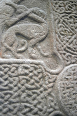 Ancient abstract design carved onto a standing stone in northern europe.  Shows animal possiblybeing hunted beside a celic cross
