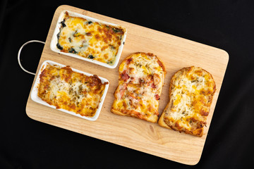 Pizza cheese toasted bread with ham cheese and imitation crab on wooden cutting boards. Isolate on black 