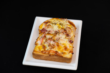 Pizza cheese toasted bread with and ham cheese on white plate. Isolate on black 