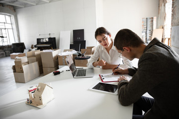 New solutions. Female estate agent showing new home to a young man after a discussion on house plans. Choosing construction materials, repair, technologies in smart house. Moving, new home concept.