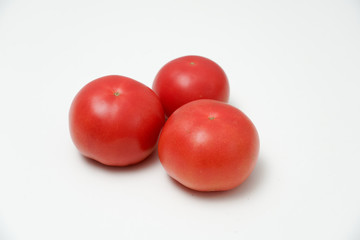 Tomato on white background. Three tomatoes placed on a white desktop.