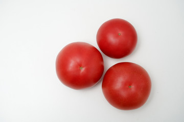 Tomato on white background. Three tomatoes placed on a white desktop