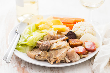 typical portuguese dish boiled meat, smoked sausages, vegetables and rice on white plate