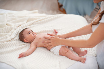 Baby massage. Masseur massaging tummy of baby during colic.