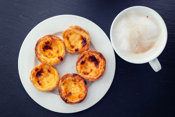 portuguese egg tart pastel de nata on white plate and cup of coffee with milk