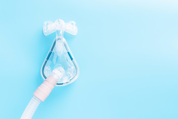 CPAP mask on blue background with copy space. Sleep apnea treatment concept. 