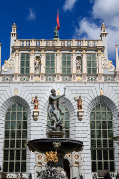 GDANSK, POLEN - 2017 AUGUST 24. Neptune Fountain Statue on Market Street (Dlugi Targ) with the historical buildings  Artus Court and city flag of Gdansk behind the statue.