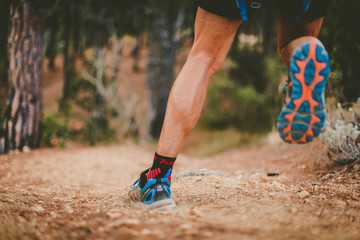 Man running down the mountain, wearing sports shoes. Close up. Copy space. Runners