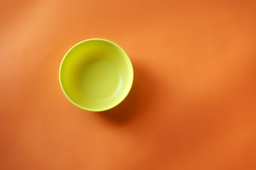 Green plastic bowl isolated on orange background                